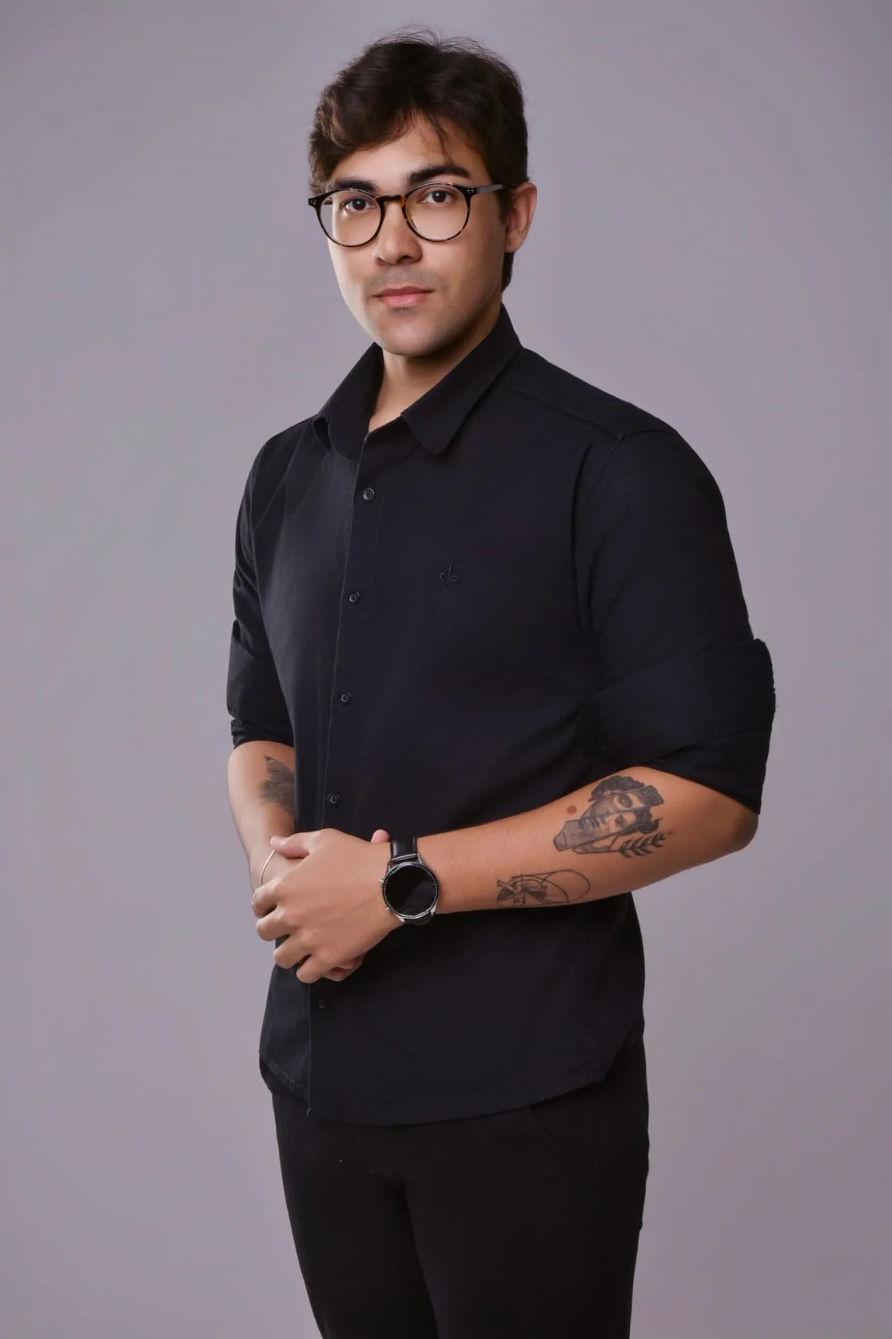 Fábson, de óculos e camisa preta, em retrato de estúdio
