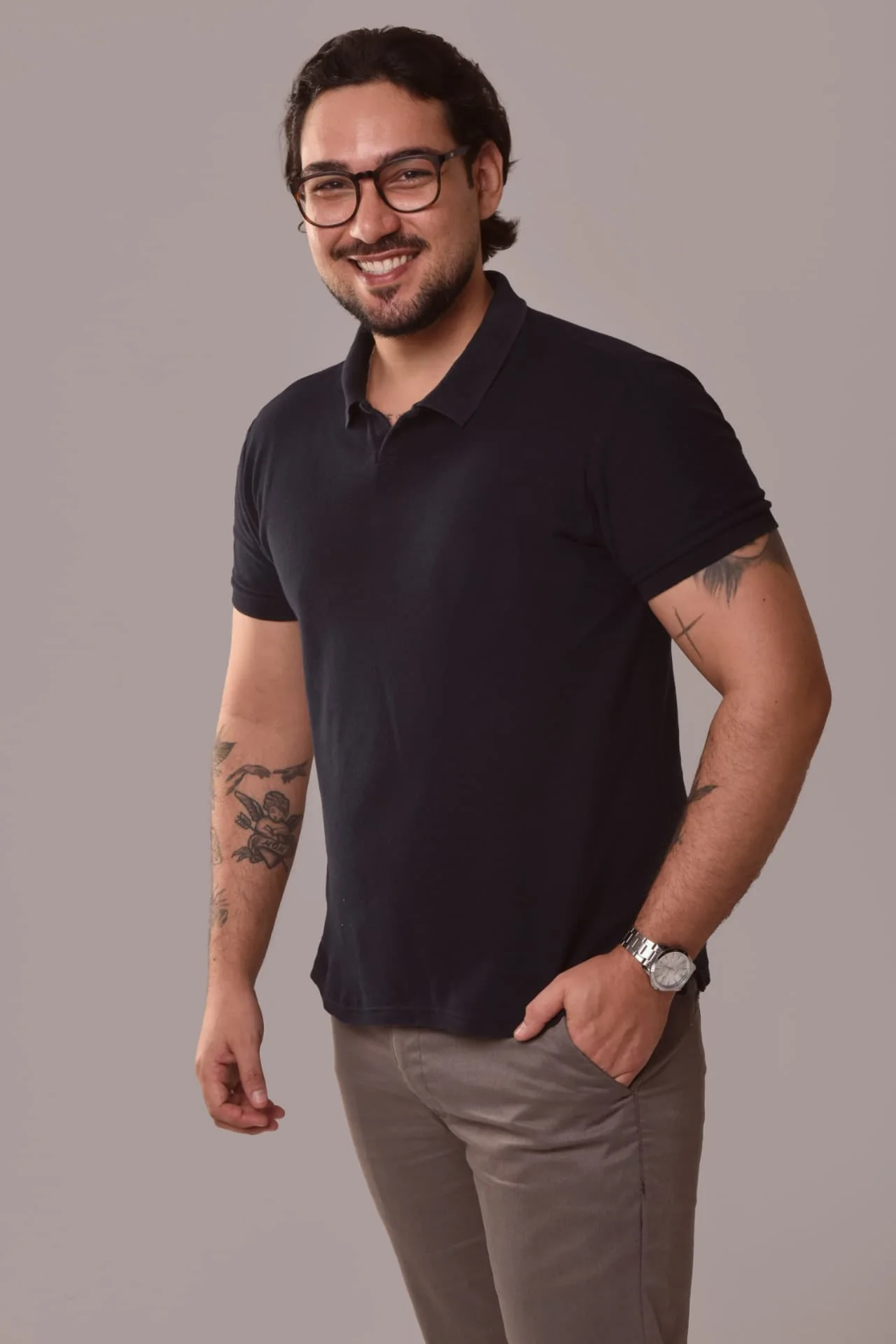 Fábio, de óculos e camisa polo escura, sorrindo em retrato de estúdio